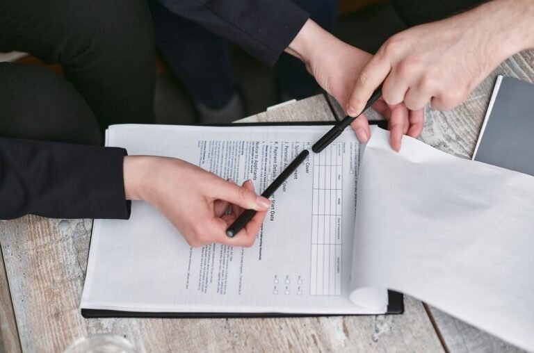 Close-up of business hands finalizing agreement with pen on documents.